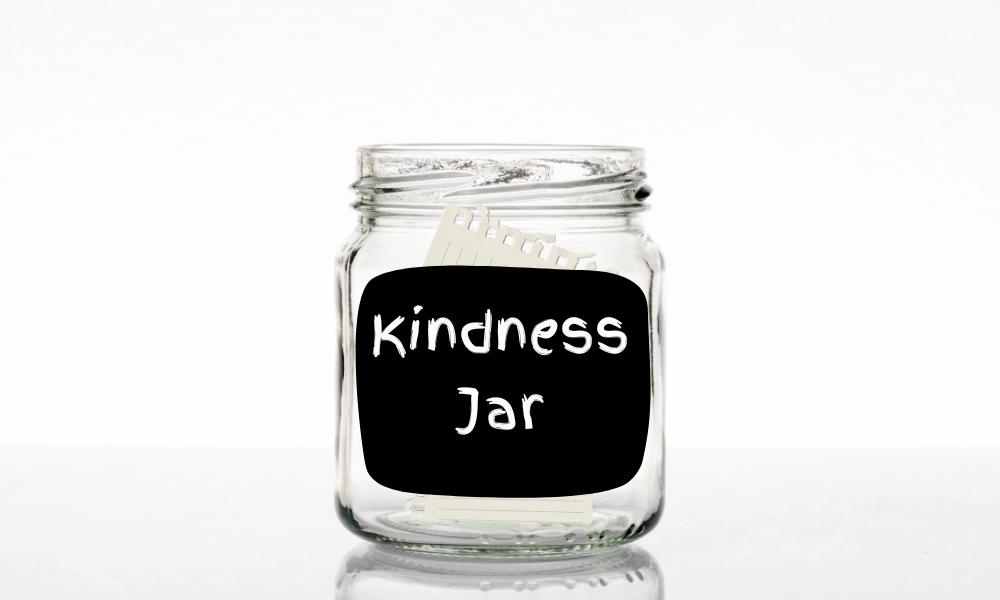 A clear jar with "kindness" sticker on it