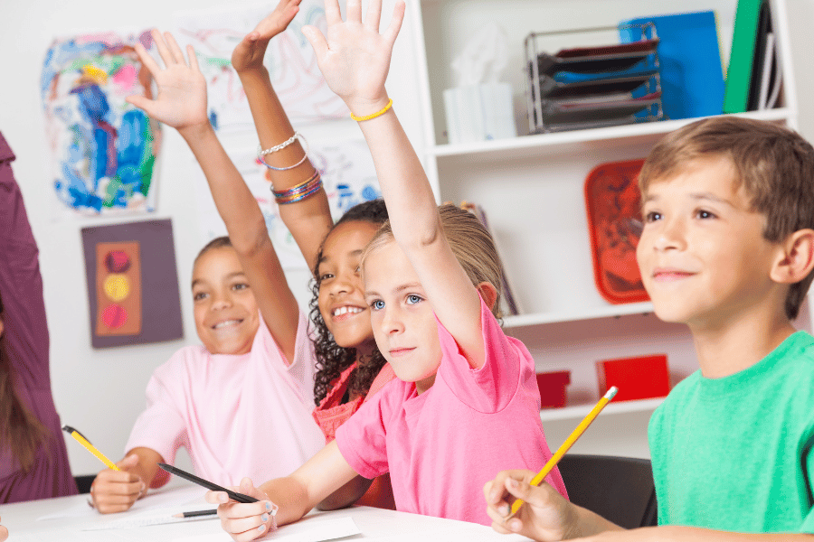 Kids raising their hands at school