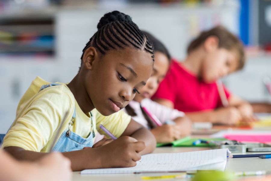 Children are writing with young black girl in the foreground