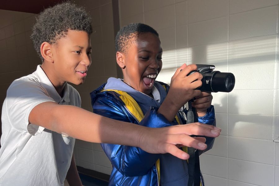 Two students pointing a camera